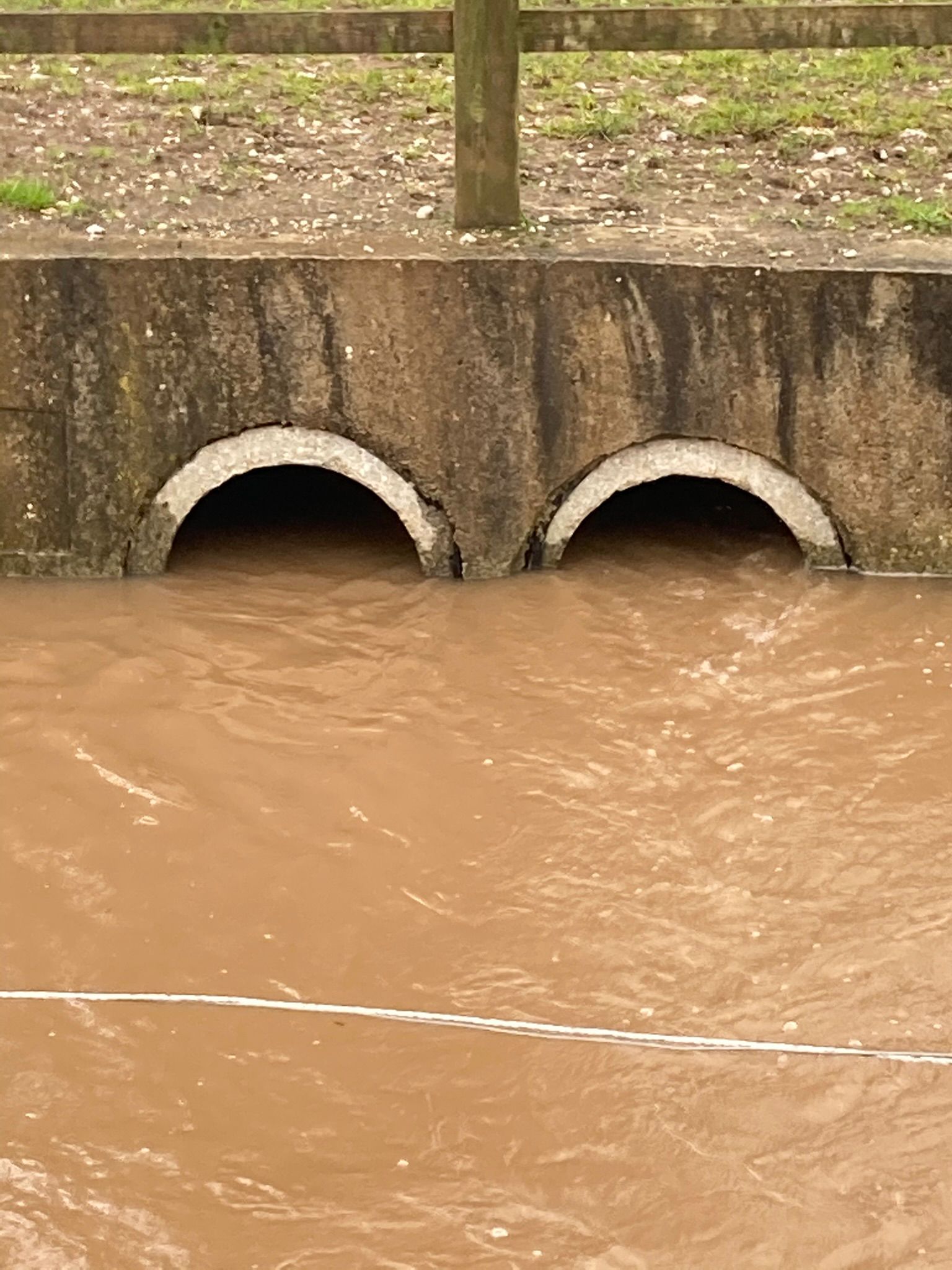 Close-up of Castle Rock Avenue culvert pipes completely submerged under floodwater